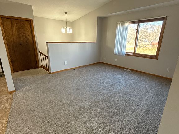 Spacious upper-level living room with vaulted ceilings and large window for natural light.