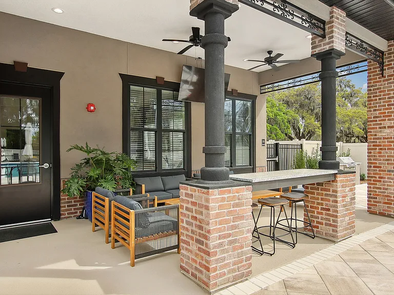Inviting outdoor patio with modern seating, chic brick pillars, and lush greenery, perfect for relaxation and entertainment.