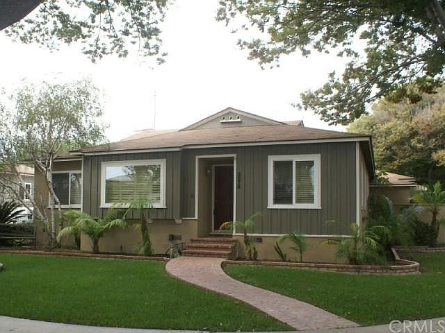 Front of home with lush green landscape & lots of trees for shade.