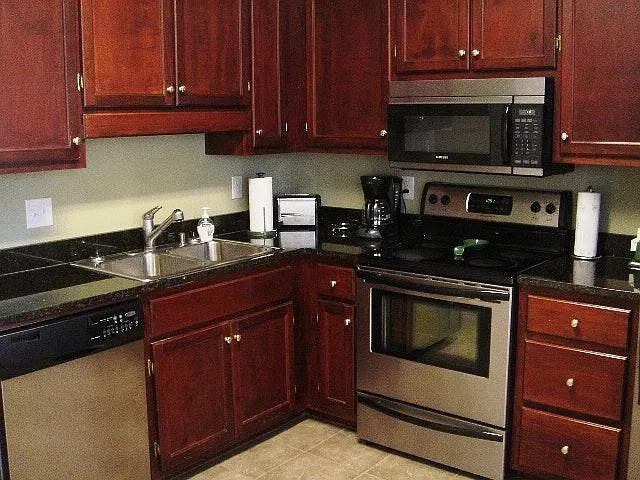 Large kitchen with loads of cabinet space and finished with stainless steel appliances, tile floors, and granite counters.