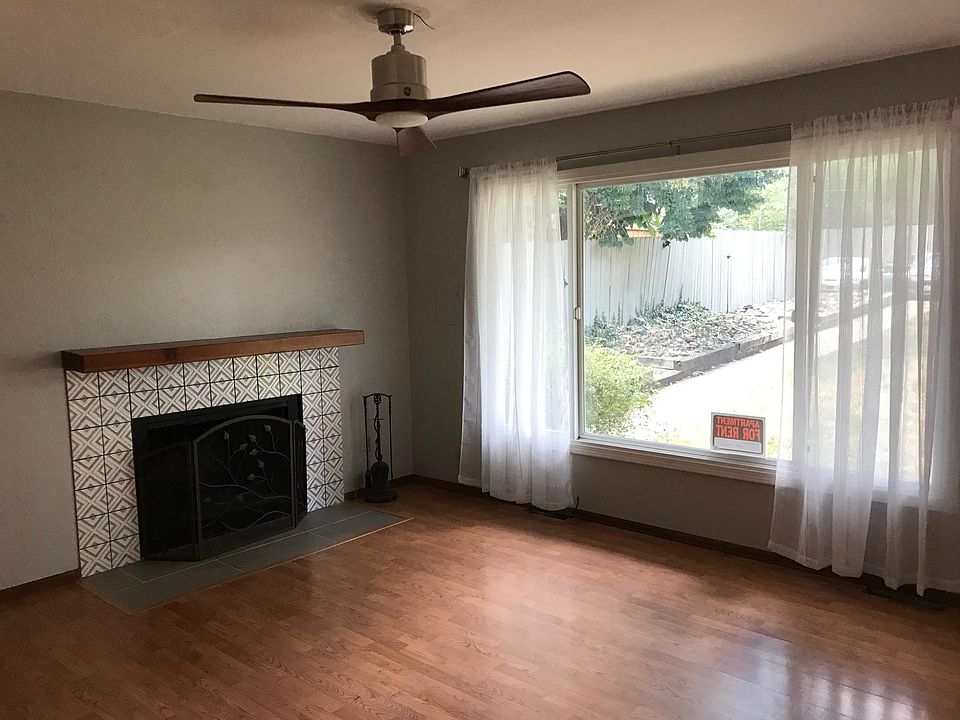 Living room with fan and wood burning fireplace