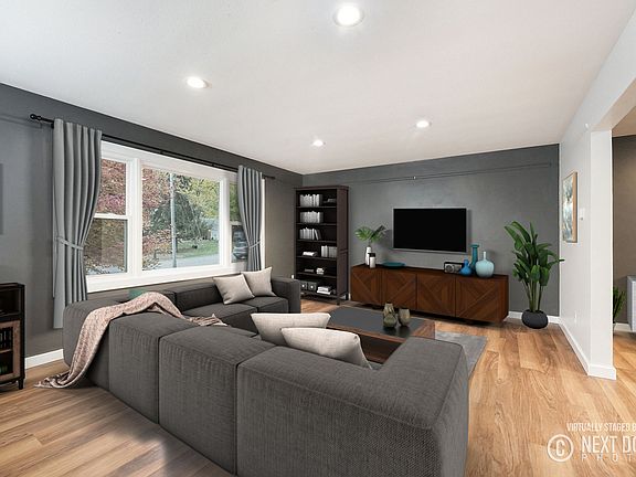 Living room with hardwood floors, recessed lighting, and large window overlooking the front yard.