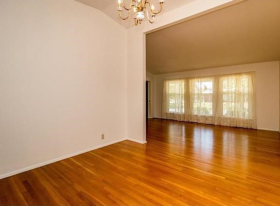 Large dining room leading into the living room with vaulted ceilings and hardwood flooring.