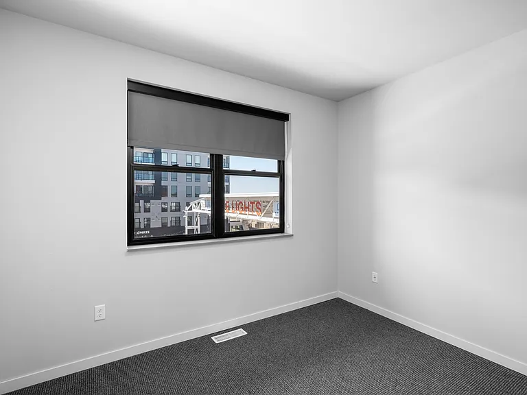 Bright, modern room with large window and sleek carpet flooring, offering a stylish and cozy living space. Bright, modern room with large window and sleek carpet flooring, offering a stylish and cozy living space.