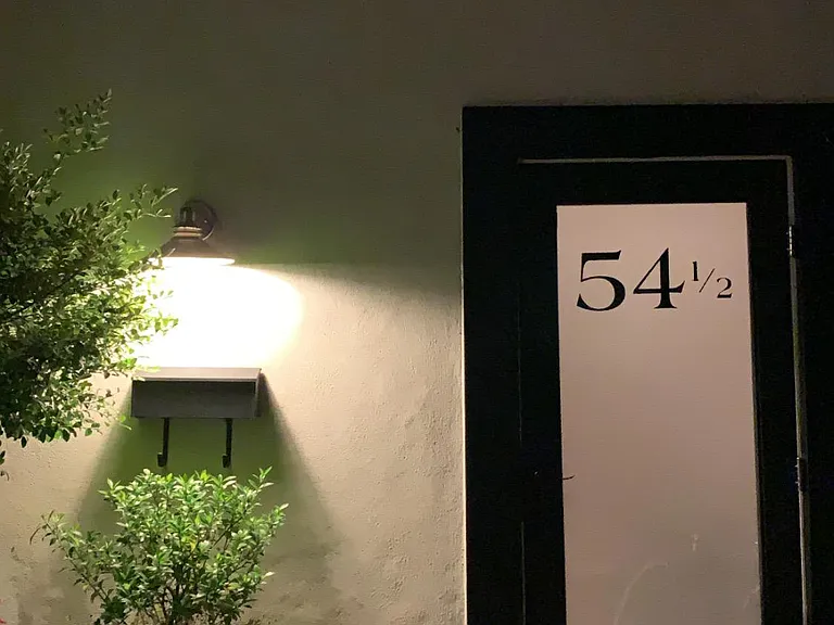 Exterior at night. The door is new! (We love it!) Your entrance is surrounded by a kitchen garden and features an iron table and chairs for your use.