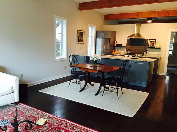 Open living/dining/kitchen with hardwood floors and exposed beams.