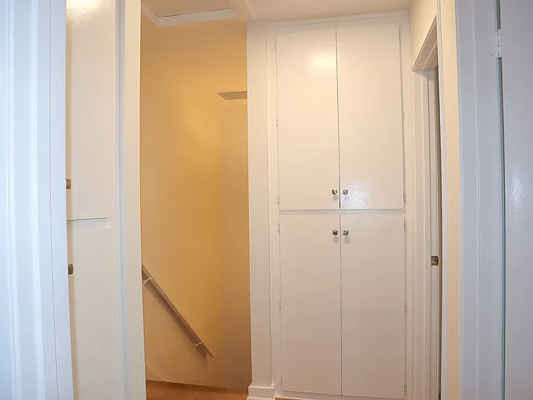 Upstairs hall storage cabinets as seen from the Primary Bedroom, with the entrance to Bedroom #2 on the right followed by the entrance to Bedroom #1.