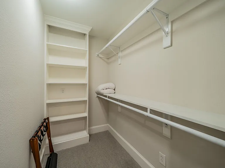 Additional storage closet with built-in shelving and hanging space for easy organization.