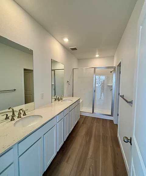 Primary ensuite bathroom featuring double sinks with lots of counter space and a large walk in closet
