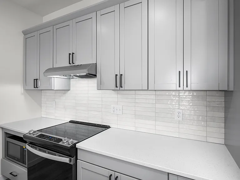 Modern kitchen with sleek white cabinetry, glossy subway tile backsplash, and stainless steel appliances. Modern kitchen with sleek white cabinetry, glossy subway tile backsplash, and stainless steel appliances.
