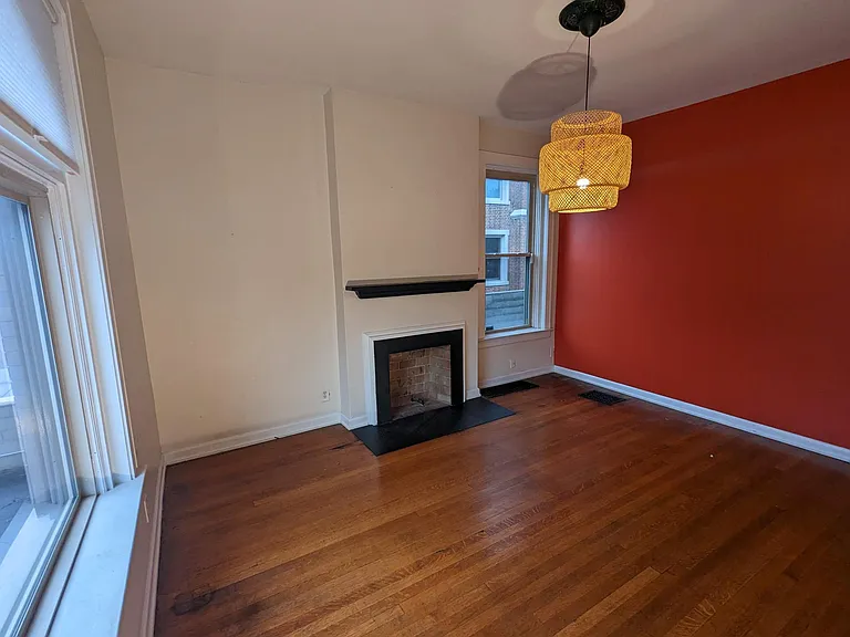 Beautiful front bedroom/dining room with original walnut hardwood floors, a non-functional fireplace, and a large closet and built-in bookshelf.