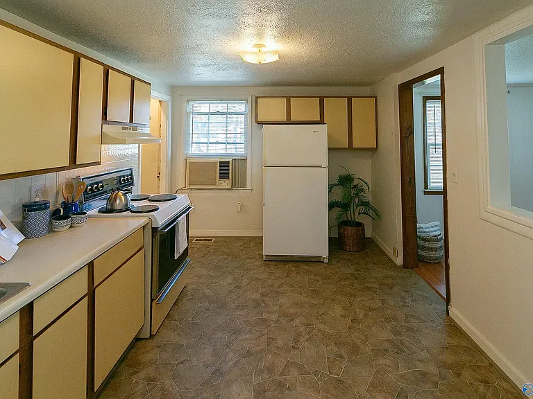 VIew of kitchen from 3rd bedroom to side yard. Living room is to the right & the laundry room is located to the left of the window.