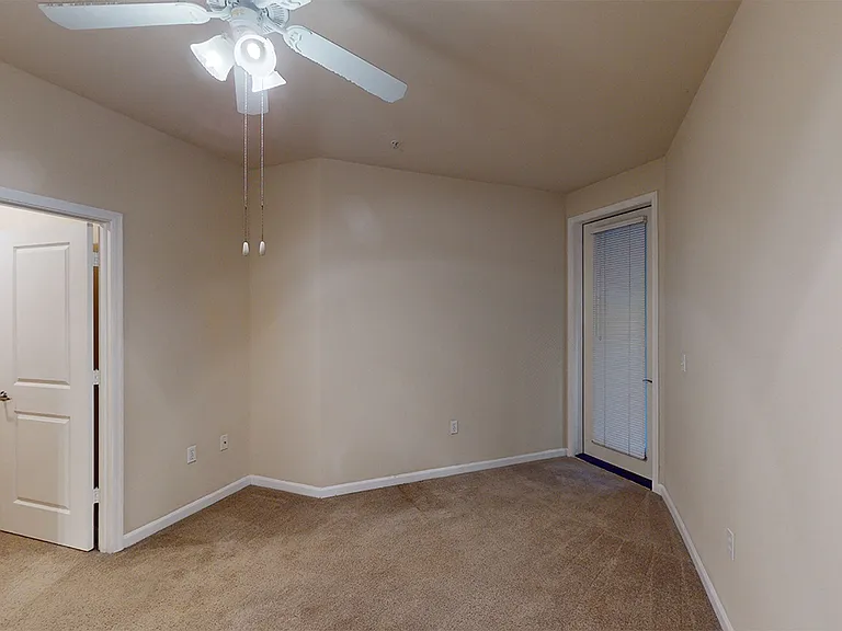 Spacious apartment bedroom with large closet and plush carpet flooring.