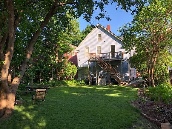 Open backyard with bonfire pit, charcoal grill, and gardening areas for plant enthusiasts.