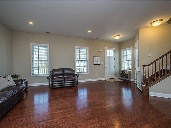 The expansive great room's tall windows fill the room with natural light.  Gleaming floors and neutral tones complimented with c