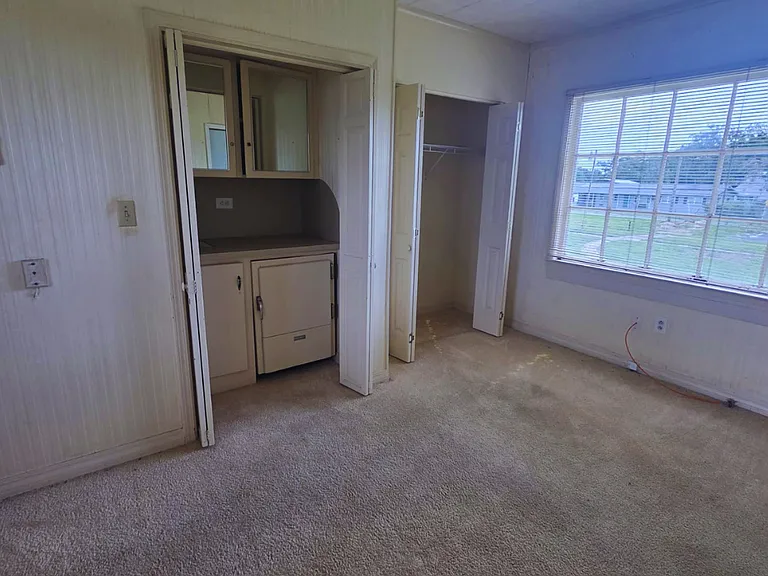 Spacious carpeted room with bright window and built-in vanity area.