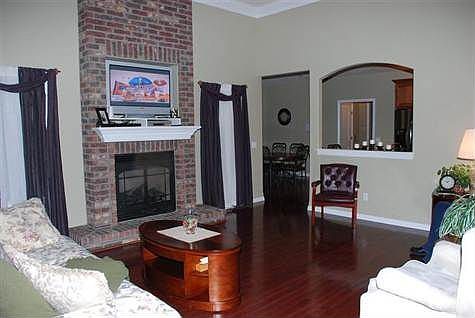 Large Living Room with natural gas fireplace and high ceiling. Overlooking back yard and Heated Salt Water In-ground Pool.