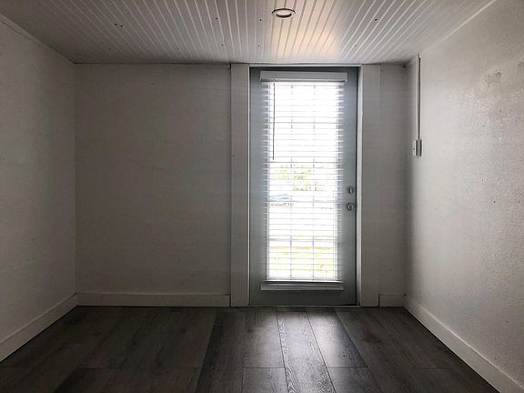 Looking at the inside/the other side of front door and the front half of living area.