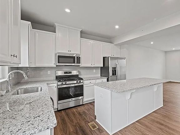 Upgraded kitchen with white cabinetry & large granite kitchen island and countertops