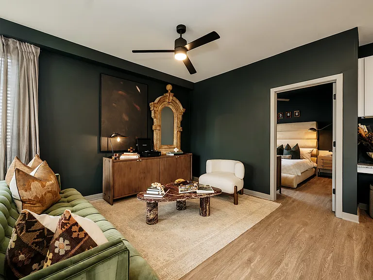 Contemporary apartment living room with ceiling fan, wood-inspired plank flooring, and designer interiors.