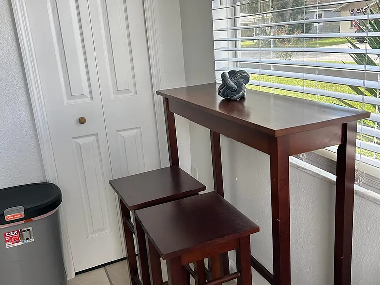 Dining area with table for two and trash bin for added convenience.