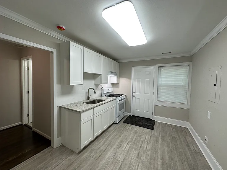 Kitchen looking toward backdoor to deck. Hallway and bathroom door in view.