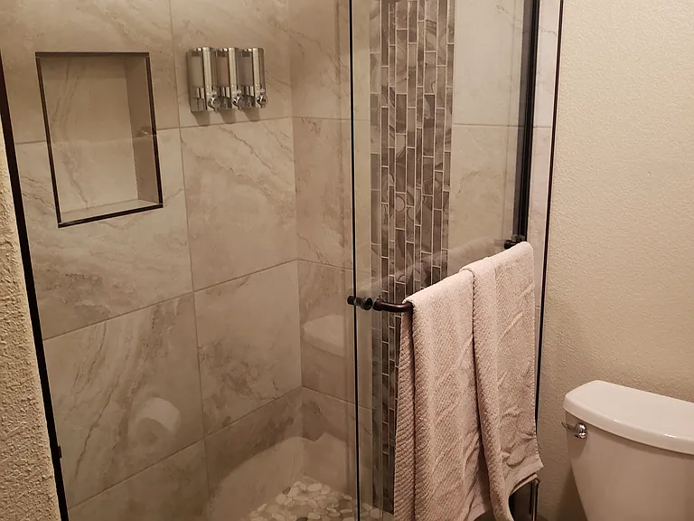 Walk-in shower with large storage cabinet for towels and essentials.