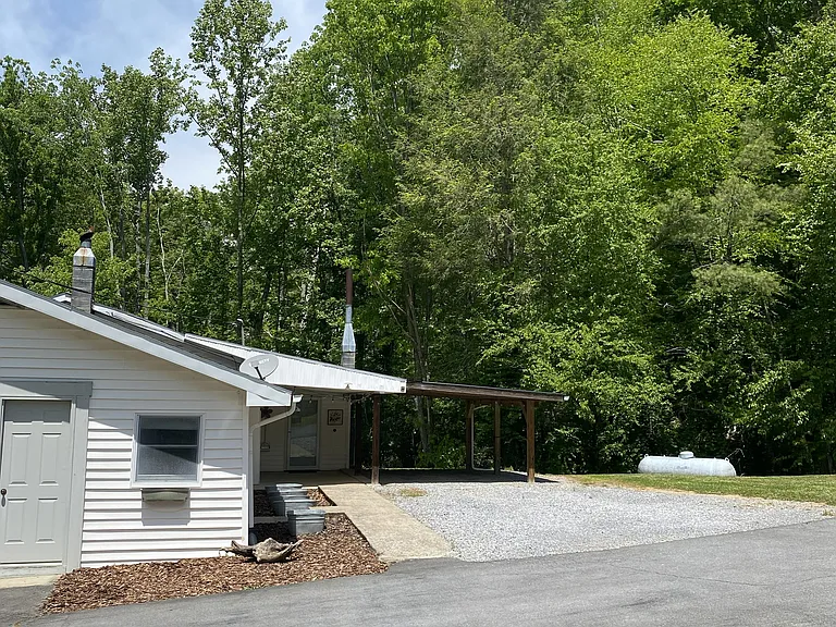 Rear entrance with covered parking and covered patio area. At the rear of the house is where you will discover the natural stream.