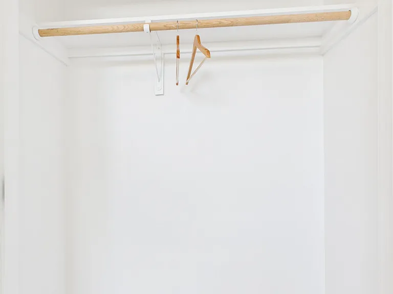 Spacious walk-in closet with a sturdy hanging rod and upper shelf, offering practical storage for clothing and essentials.