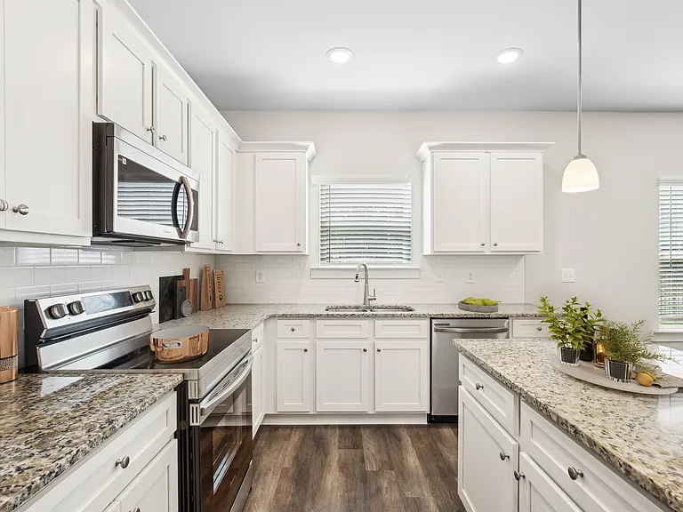 Spacious kitchen with an island, ample storage, stainless steel appliances and view into the living room.