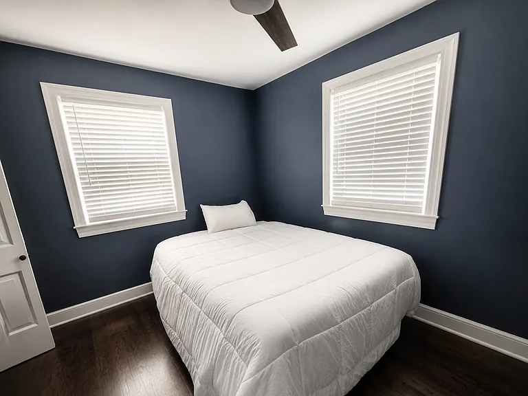 This spacious secondary bedroom offers expanded closet space, a modern ceiling fan with remote control, and abundant natural light for year-round comfort.
