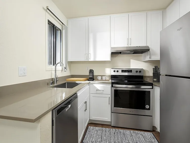 Renovated I kitchen with grey quartz countertops, white cabinetry, stainless steel appliances, and hard surface flooring