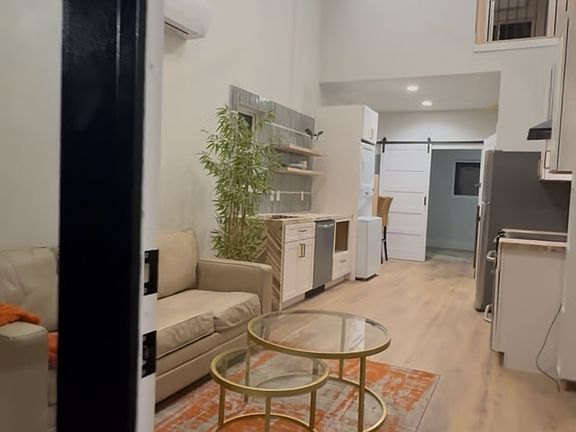 View of the entrance opening into a spacious, open-concept cottage/guest house featuring dramatic 22-foot ceilings and sleek, modern design.