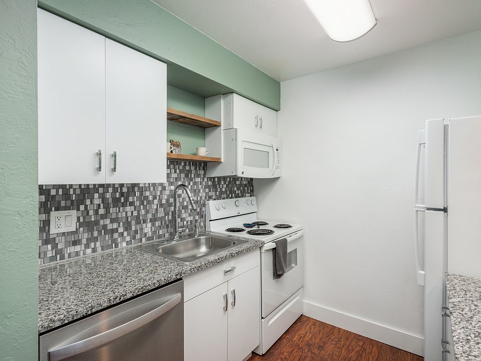 Updated kitchen with granite countertops, cute wood shelving, and modernized backsplash tile.