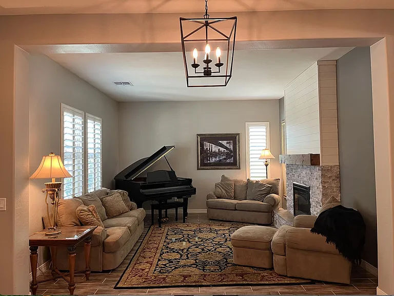 Front room with couch, loveseat, fireplace, piano and chair w/ottoman