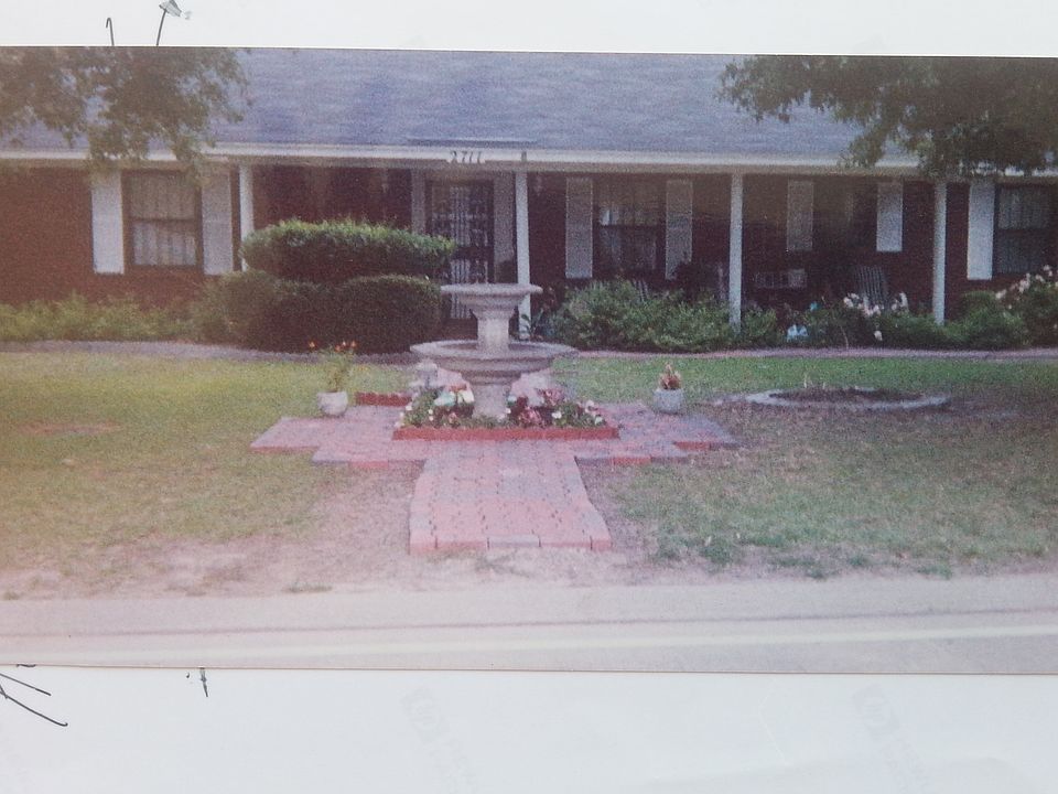 Front view;showing flowerbeds, yard, trees, two brick walkw