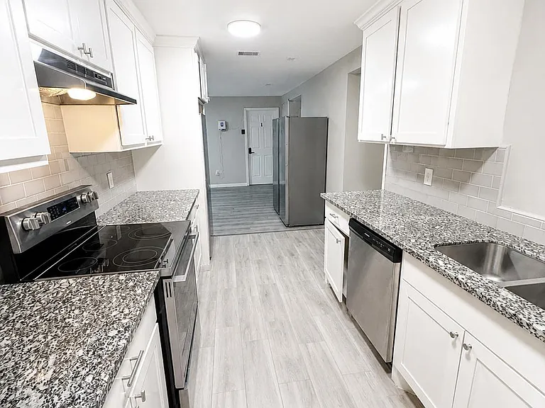 Galley kitchen with generous counter space, ample cabinetry, tile backsplash, and stainless appliances for easy meal prep.