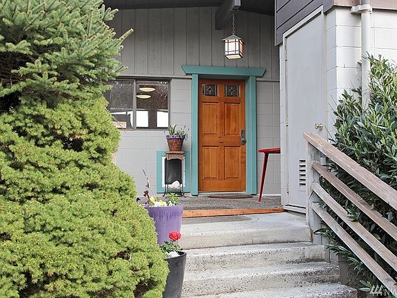 An inviting covered porch entry.  Door to the right (top of stairs) leads to a small basement/utility room.  Deck to the left has space for an outdoor dining area. Deck wraps around to the front of the home!