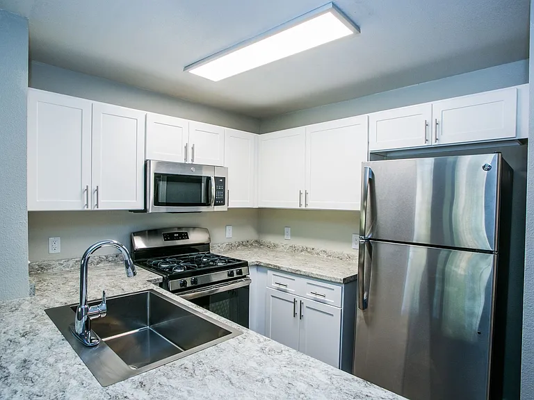 Fully equipped kitchen with stainless steel appliances, white shaker cabinets, and granite counters.