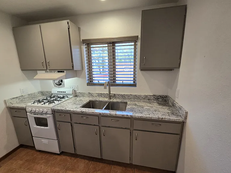 Kitchen area with gas stove, cabinets and new granite tops with stainless steel sink