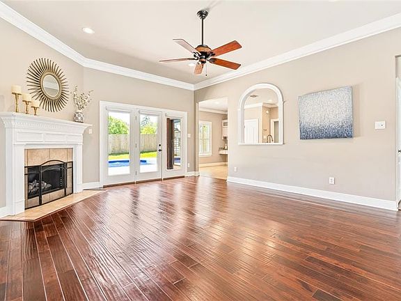 Unfurnished living room with ornamental molding, a fireplace, ceiling fan, and dark hardwood / wood-style flooring
