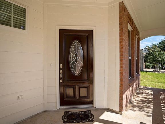 Protected covered front porch leads to a welcoming entry door with oval leaded glass insert.
