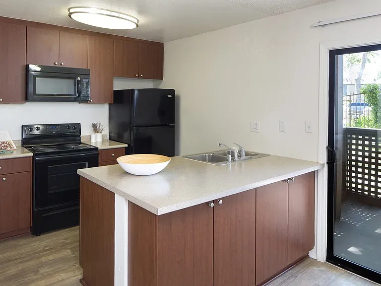 Classic Package II kitchen with black appliances, dark cherry cabinetry, beige laminate countertops, and hard surface flooring