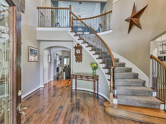Stunning entry with winding spindled staircase with decorator ledge, scraped wooden floors and high ceilings. The formal dining room is on the right and the den is located on the left. Formal living room is through the arched doorway ahead.
