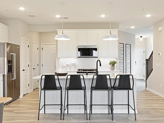 Stainless steel appliances, gas stove, dishwasher, microwave, refrigerator. Model home pictures for furniture placement ideas.