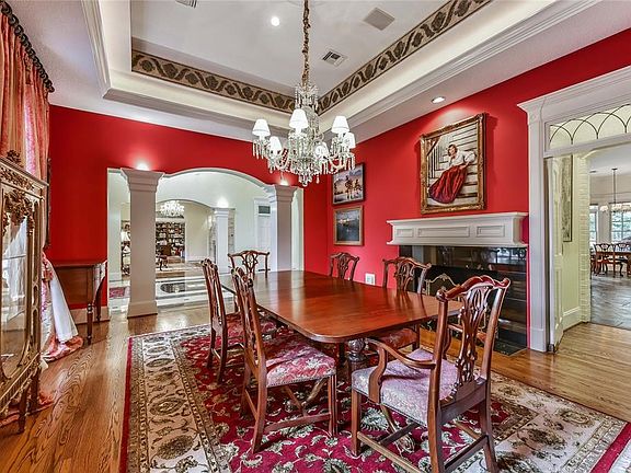 The elegant Formal Dining Room features a marble surround gas fireplace, tray ceiling and hardwood floors .  Through the doorway is the butlers bar and wine refrigerator and leads to kitchen.