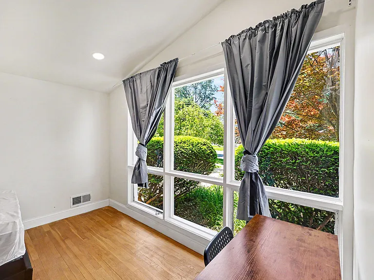 Bedroom with large picture windows, hardwood floors, and room for a bed and small desk or seating area.