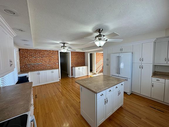 Kitchen facing exposed brick wall and eat in table area with built in bench