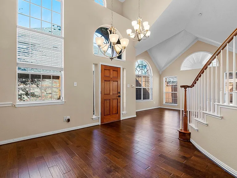 Two-story foyer featuring wood-finish flooring, a vaulted ceiling, and multiple arched and rectangular windows