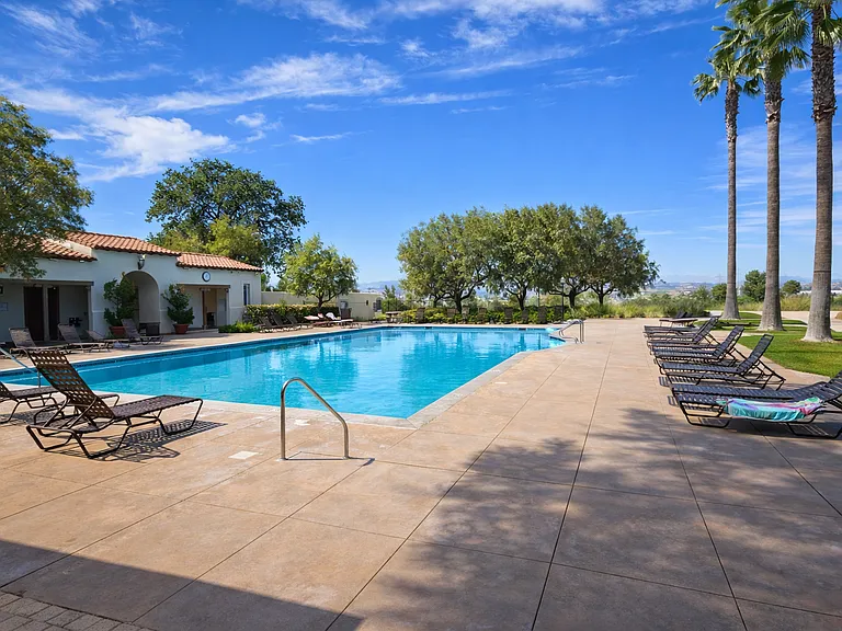 Private gated community pool with resort-style setting, featuring a large sparkling pool, relaxing jacuzzi, lounge chairs, shaded seating areas, and beautifully maintained grounds. Includes convenient access to changing rooms & a dedicated BBQ & picnic